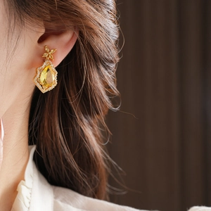 Macro detail of luxury water-drop earring with yellow gemstone and diamonds on a model