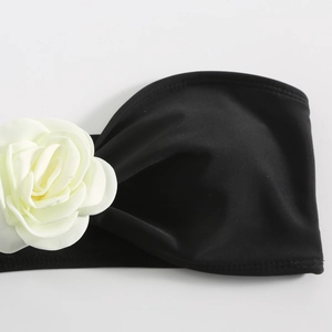 Detail of black elastic bikini band with a 3D white rose floral applique texture