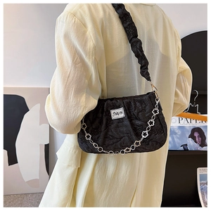 Detail of black pleated underarm bag featuring a unique silver flower chain strap