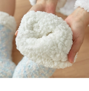 Close-up of thick white faux shearling lining inside a blue knitted winter slipper sock