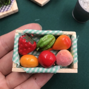 Close-up of miniature wooden fruit box with tiny resin strawberries and mangoes