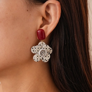 Close-up of retro floral earring with polka dot layers and deep red rectangular stud