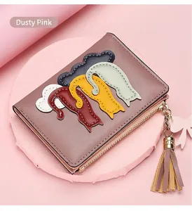 Close-up of pink leather wallet featuring cartoon cat patches and a tassel keychain