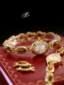 Macro shot of a vintage gold tiger eye stone watch with a textured red background