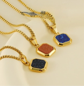 Détail de trois colliers en acier inoxydable doré avec pendentifs en pierres colorées