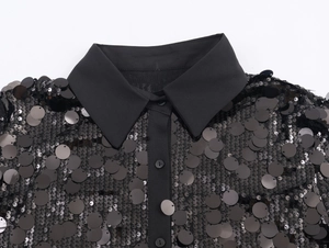 Close-up of black sequin blouse featuring a classic collar and single-breasted button detail