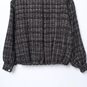 Dettaglio della trama in tweed bianco e nero e dei bottoni metallici sui polsini