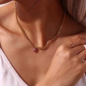 Detail of gold curb chain necklace with heart purple zircon and matching rings