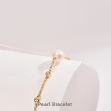 Detail of gold chain bracelet featuring clear zircons and a round freshwater pearl