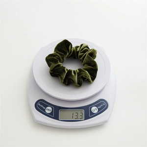 Deep green velvet scrunchie shown on a digital scale weighing 13.3g for quality assurance