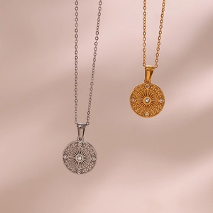 Detailed close-up of gold and silver compass pendants with cubic zirconia on silk