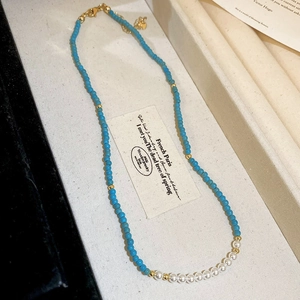 Détail du collier de perles d'eau douce avec perles bleues et cœur doré sur plateau
