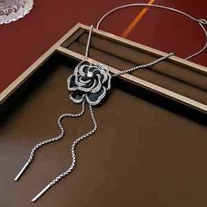 Detail of black enamel camellia necklace with silver rhinestones and long tassel chains