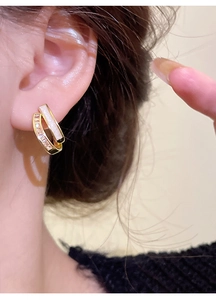 Close-up of model wearing gold double-row earrings with white inlay and zircon accents