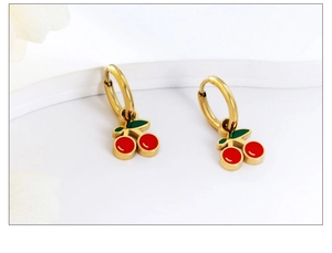 Close-up of cute cherry drop earrings with red fruits and green leaves on gold hoops