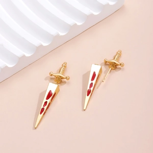 Detailed macro view of gold gothic sword earrings with red enamel blood drip effect