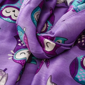 Detailed view of soft purple textile fabric featuring colorful cartoon owl pattern prints