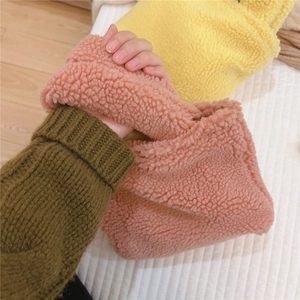 Gros plan de sacs à main en laine d'agneau rose et jaune sur un fond matelassé doux