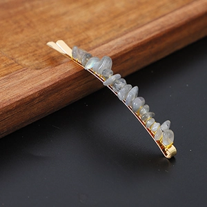 Detail of gold bobby pin with grey-blue natural crystal stones on a wooden tray