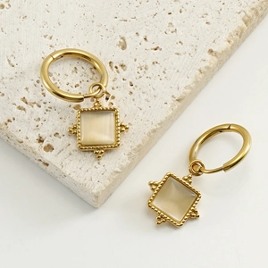 Detail of square cat eye stone earrings in 18k gold finish with beaded metal texture