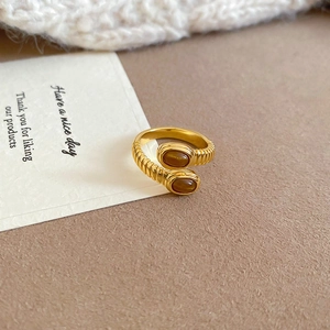 Detail of gold spiral open ring featuring dual oval brown tiger eye stones on a card