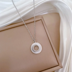 Macro detail of a silver stainless steel circular pendant on a luxury silk background