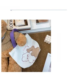Detail of white canvas tote bag with purple handles and cute cartoon bear print