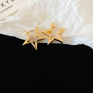 Close-up of golden star-shaped hoop earrings with polished finish on black background