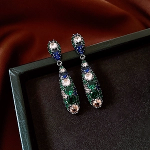 Detailed close-up of vintage drop earrings with multi-colored crystals on a black jewelry box