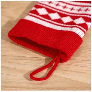 Close-up of red and white knitted Christmas stocking with a hanging loop on wood