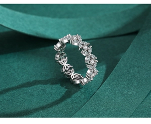 Macro shot of silver floral ring with marquise cut stones on a dark green surface