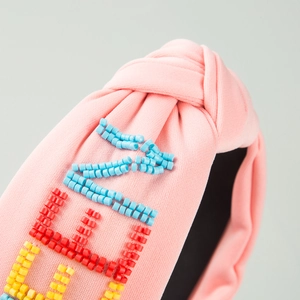 Bandeau à nœud torsadé rose avec décorations de lettres en perles colorées