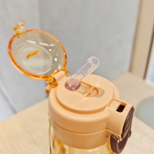Close-up of beige Capybara water bottle lid with orange flip cap and silicone straw