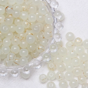 Detailed macro view of 8mm translucent white glass beads with delicate gold vein patterns