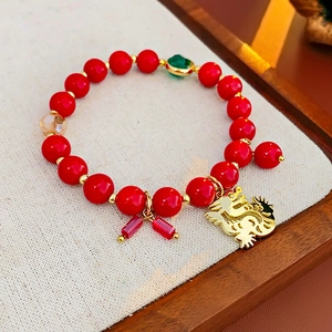 Détail du bracelet en perles rouges avec pendentif dragon doré et charmes traditionnels