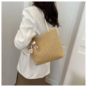 Sac fourre-tout en paille avec nœud en soie fleurie porté par un mannequin élégant