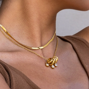 Close-up of layered 18K gold stainless steel snake chain and rhinestone pendant necklaces
