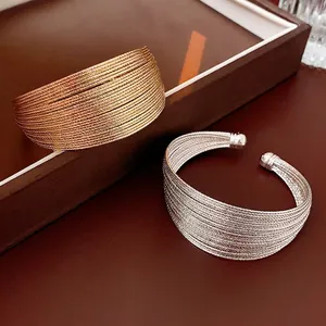 Gold and silver multi-layer wire mesh open cuff bracelets on luxury leather tray