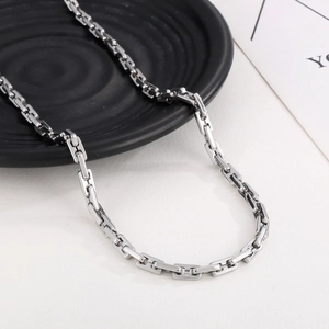 Close-up of silver rectangular link chain necklace on a black and white background
