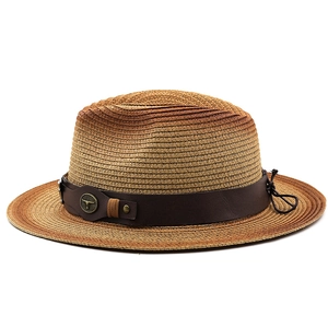 Détail d'un chapeau de paille à large bord avec bande en cuir et ornement taureau