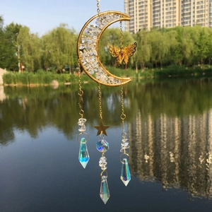 Close-up of golden butterfly crystal suncatcher hanging against a natural lake backdrop