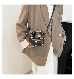 Detail of a black moon-shaped bag with silver stud rivets and a detachable shoulder strap