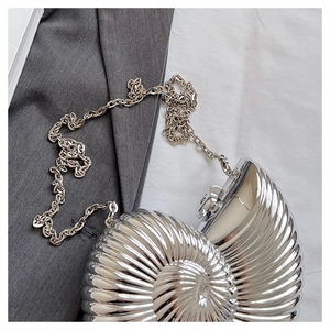 Macro detail of silver shell-shaped evening bag featuring metallic texture and chain strap