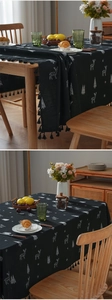 Close-up of black Christmas tablecloth featuring white reindeer embroidery and tassels