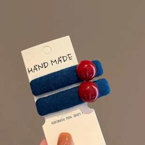 Handmade navy blue and red hair clips set with resin beads shown on card packaging