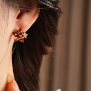 Detail of gold plated star earring with a small deer motif and zircon on ear lobe