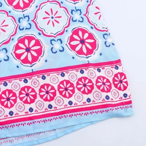 Close-up of floral print fabric with pink flowers on light blue cotton dress hem