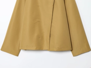 Detailed close-up of the hem and cuffs on a khaki minimalist loose short trench coat