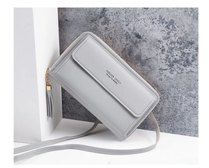 Detail of light grey faux leather crossbody bag with metal tassel and elegant typography