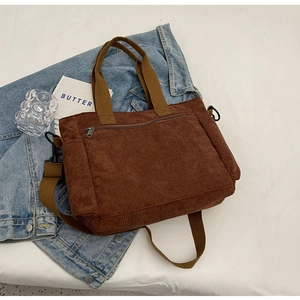 Detail of a brown corduroy tote bag with front zipper pocket and adjustable strap